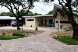 Modern driveway with a mix of concrete and natural stone, accented by greenery and stylish pathway lighting.